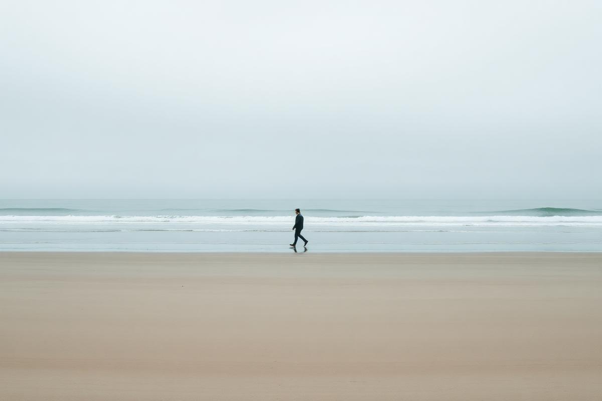 A person walking alone on a wide shoreline at low tide